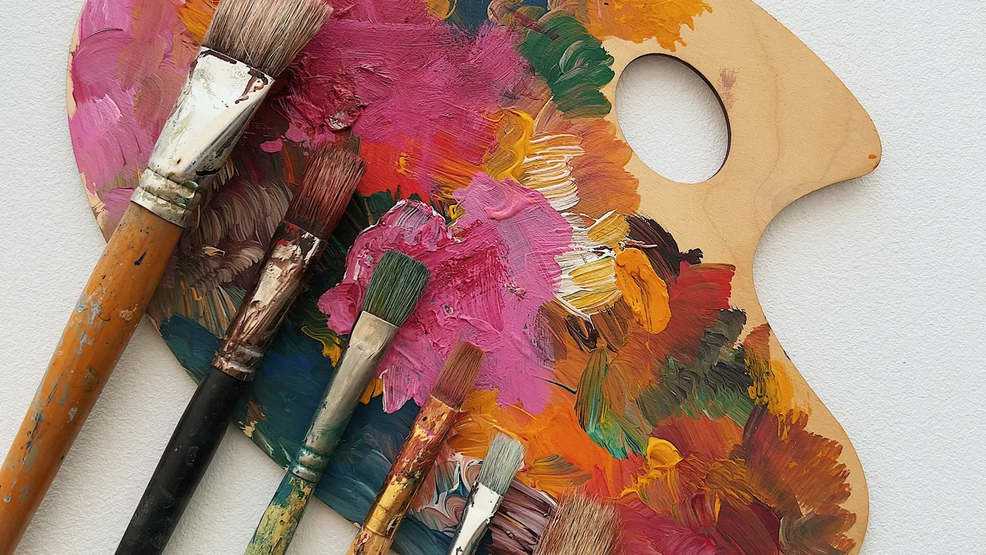 Paintbrushes resting on a wooden palette covered in oil paint
