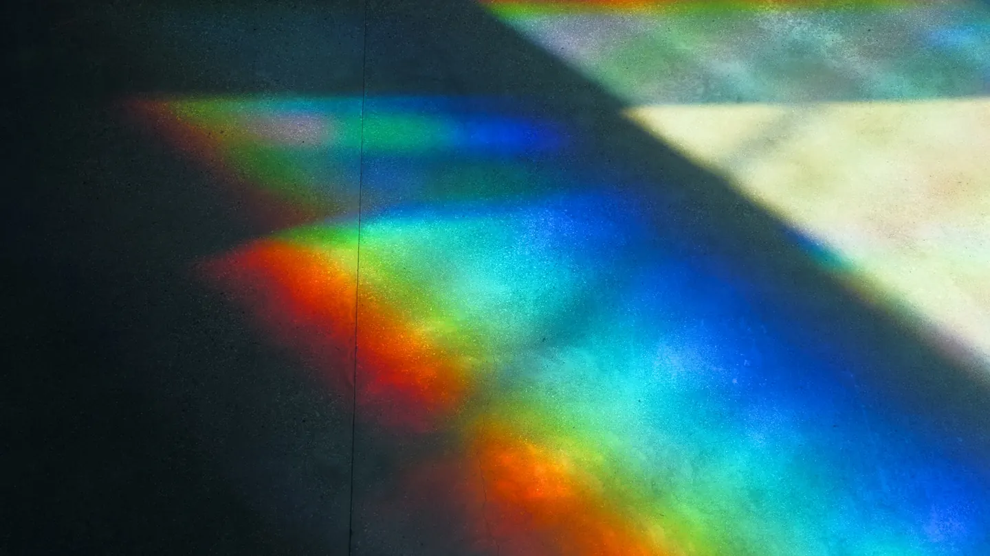 A beam of light split into the colours of the rainbow on a dark surface